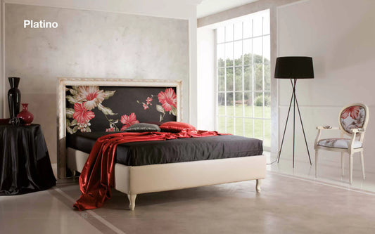 Letto matrimoniale classico con struttura laccata oro con motivi floreali e rivestimento con tessuto a motivi floreali.